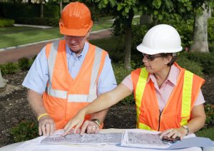 Two engineers working on a construction project together looking over the layout.