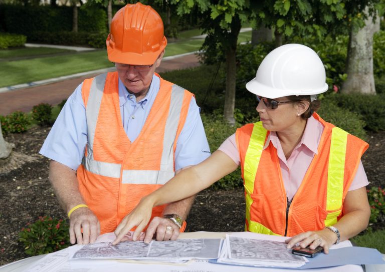 Two engineers working on a construction project together looking over the layout.
