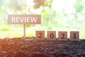 signs reading "2021" & "review" on top of fertile soil