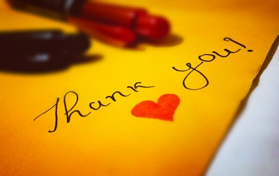 yellow paper and pens with "Thank You!" and a heart drawn on paper