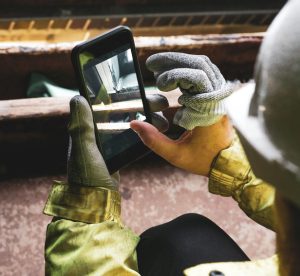 construction worker uses smartphone to photograph commercial construction project