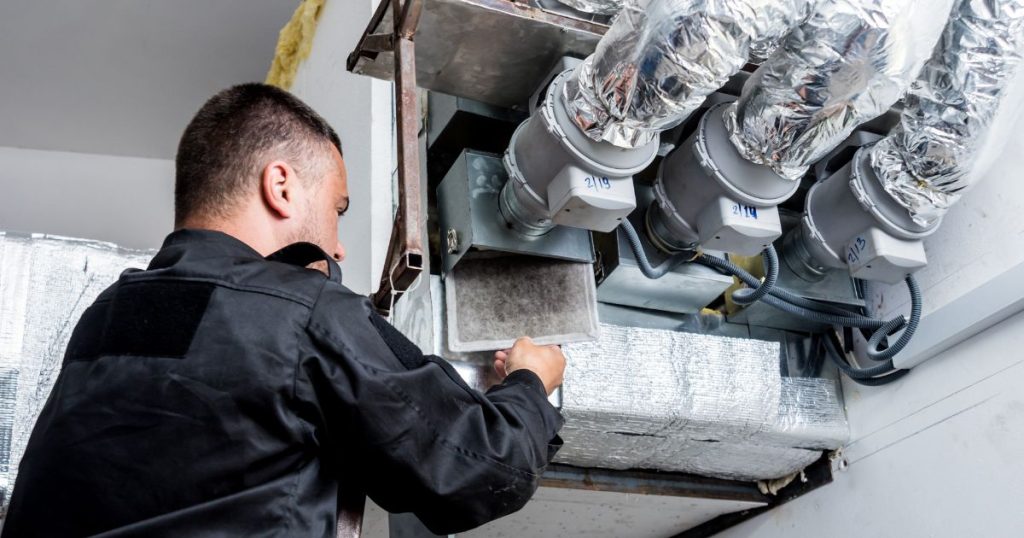 Man in black shirt performing maintenance on commercial building HVAC system